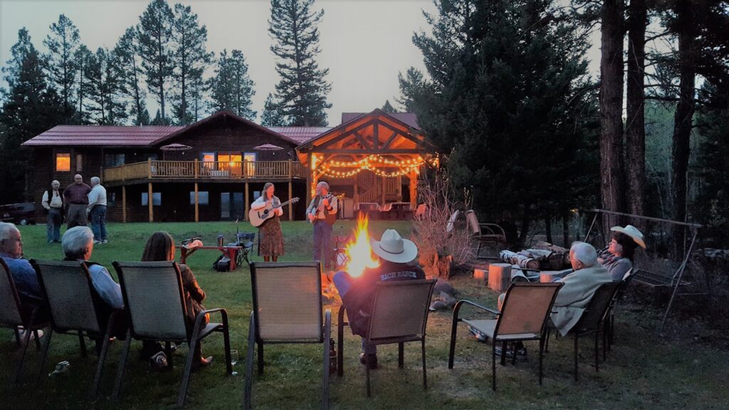 Guests enjoy an evening campfire and live entertainment on the lawn overlooking the meadow